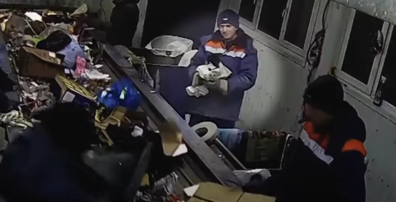 man rescuing cat at recycling plant