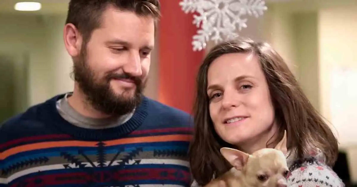 couple holding tiny rescue dog they adopted